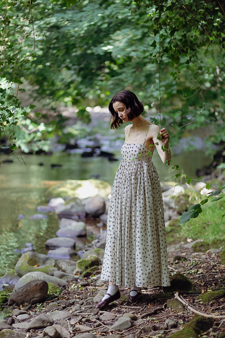 Woman in a polka dot dress standing by a stream in a forest