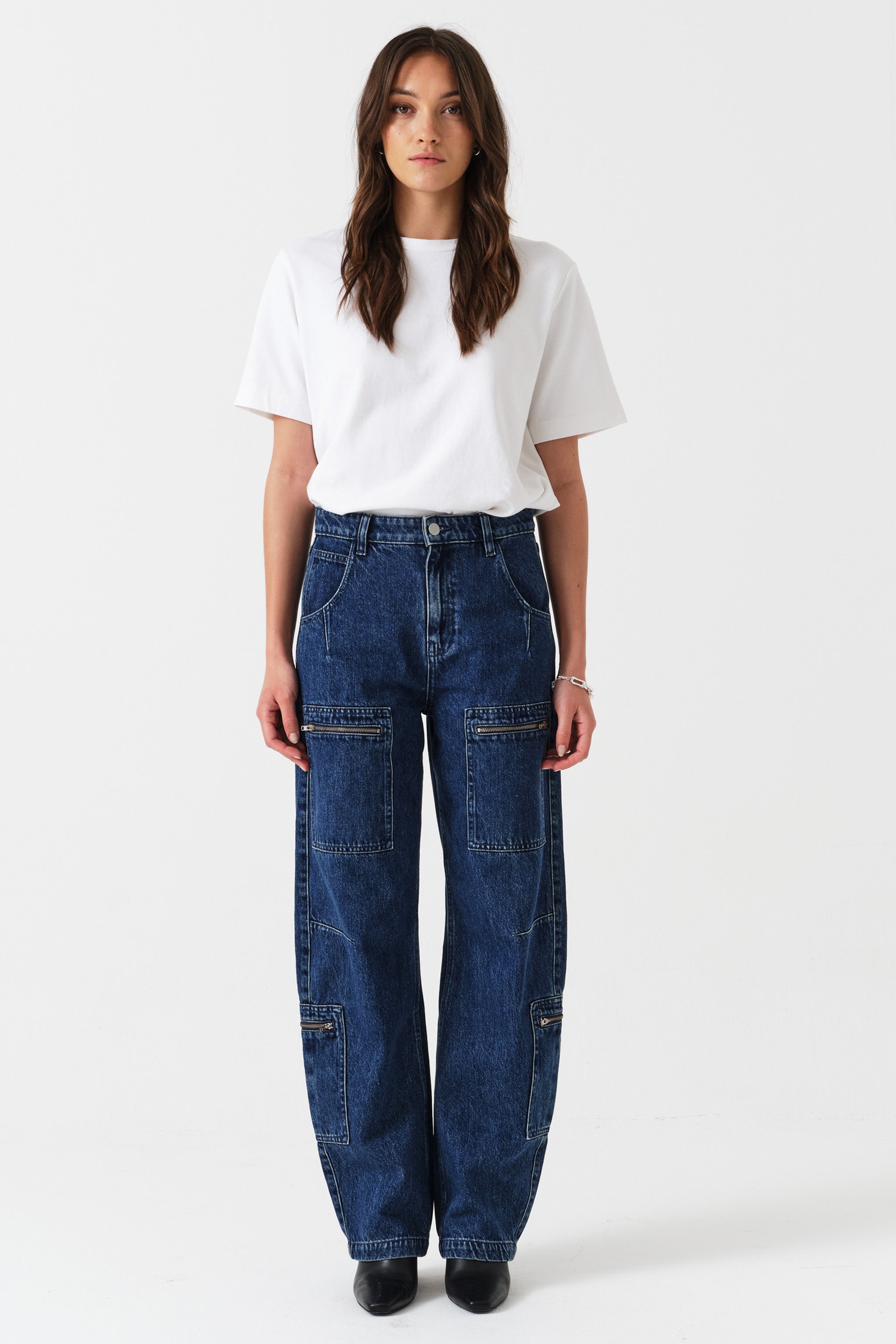 Woman wearing a white t-shirt and blue jeans with zip details on a white background