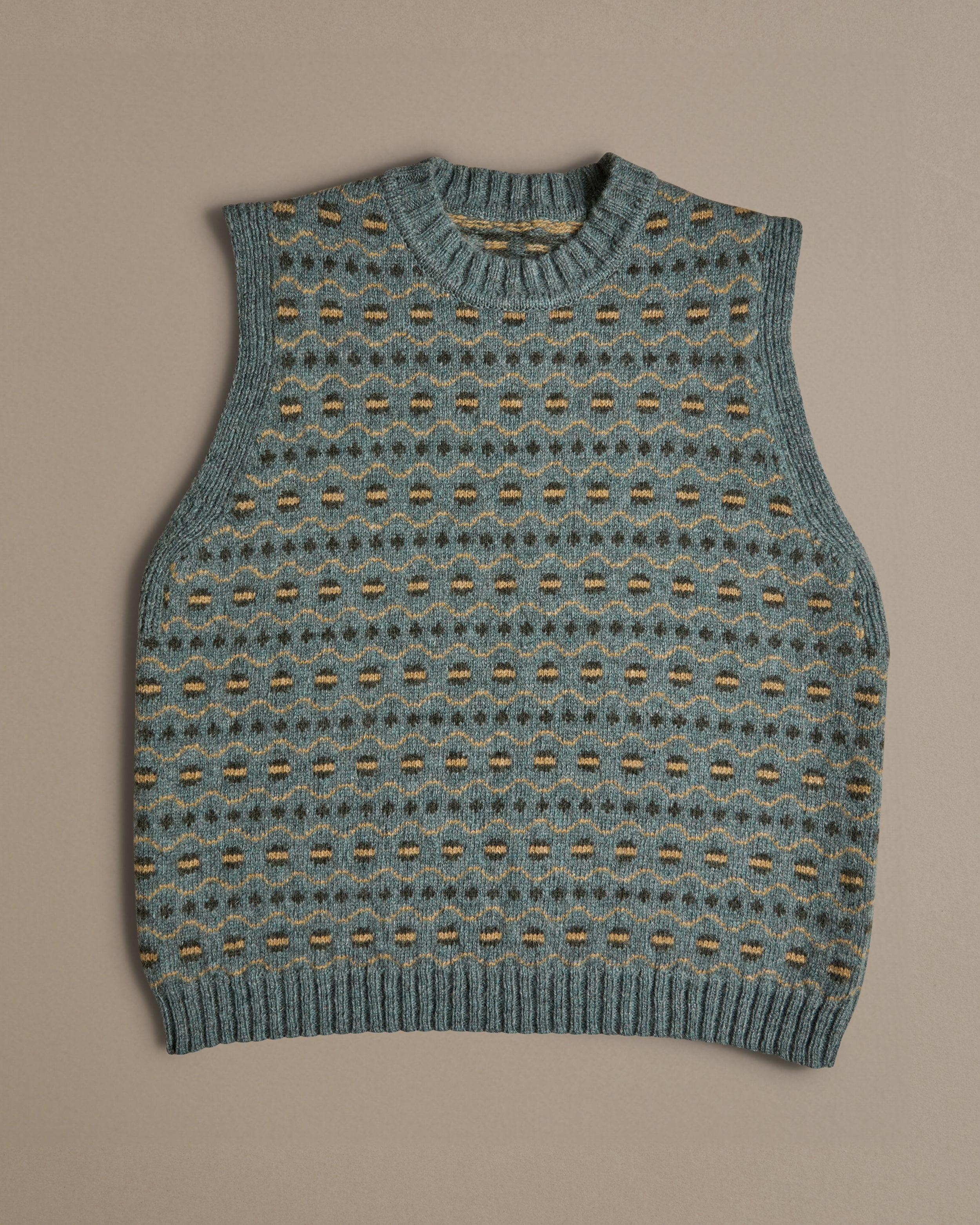 A blue vest with a Fair Isle pattern. Knitted in Scottish spun wool, designed and made in the UK.