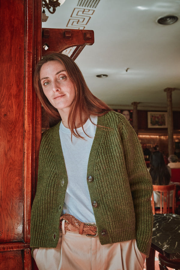 Person wearing a green cardigan in an indoor setting