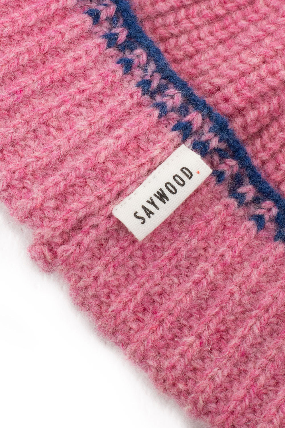Close-up of the pink beanie’s ribbed knit, blue crochet trim and woven Saywood label, made in Britain
