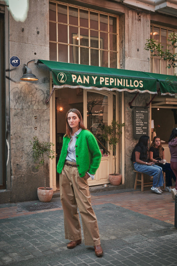 Woman in a green cardigan standing in front of a store 