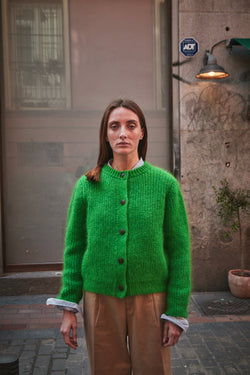 Woman wearing a green cardigan standing in an urban setting