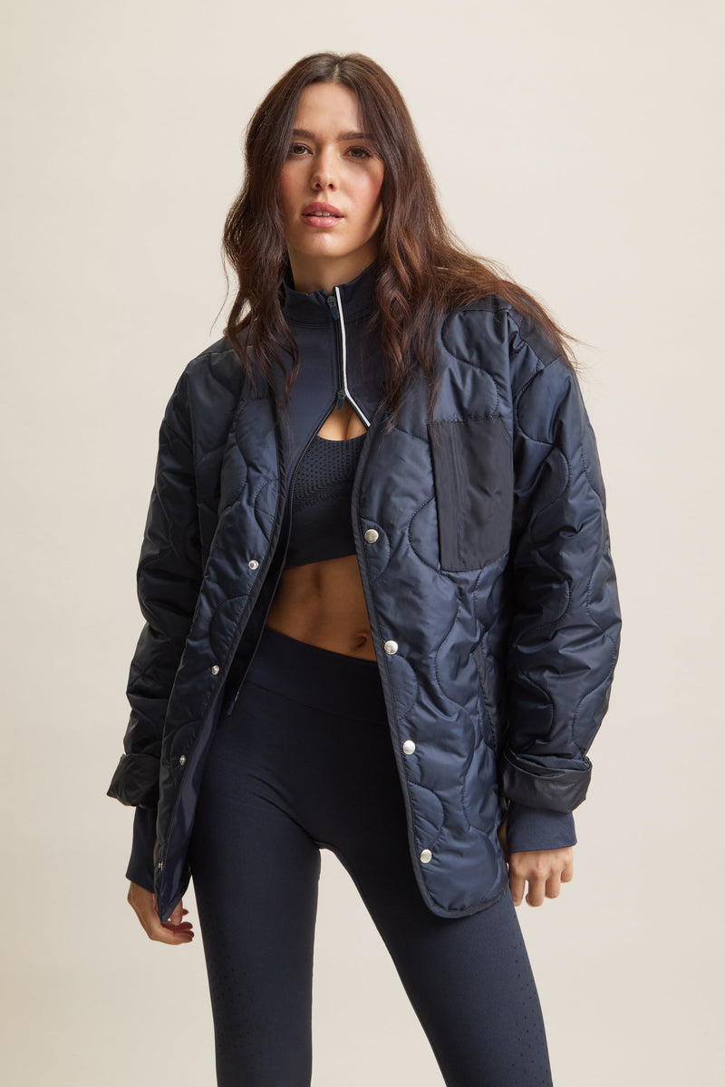 Women's HRMN8 navy dark blue wave-quilted jacket with chest pocket and side pockets, lightweight layering piece for athleisure, streetwear, and activewear. Versatile, breathable, and ideal for transitional weather and everyday movement.