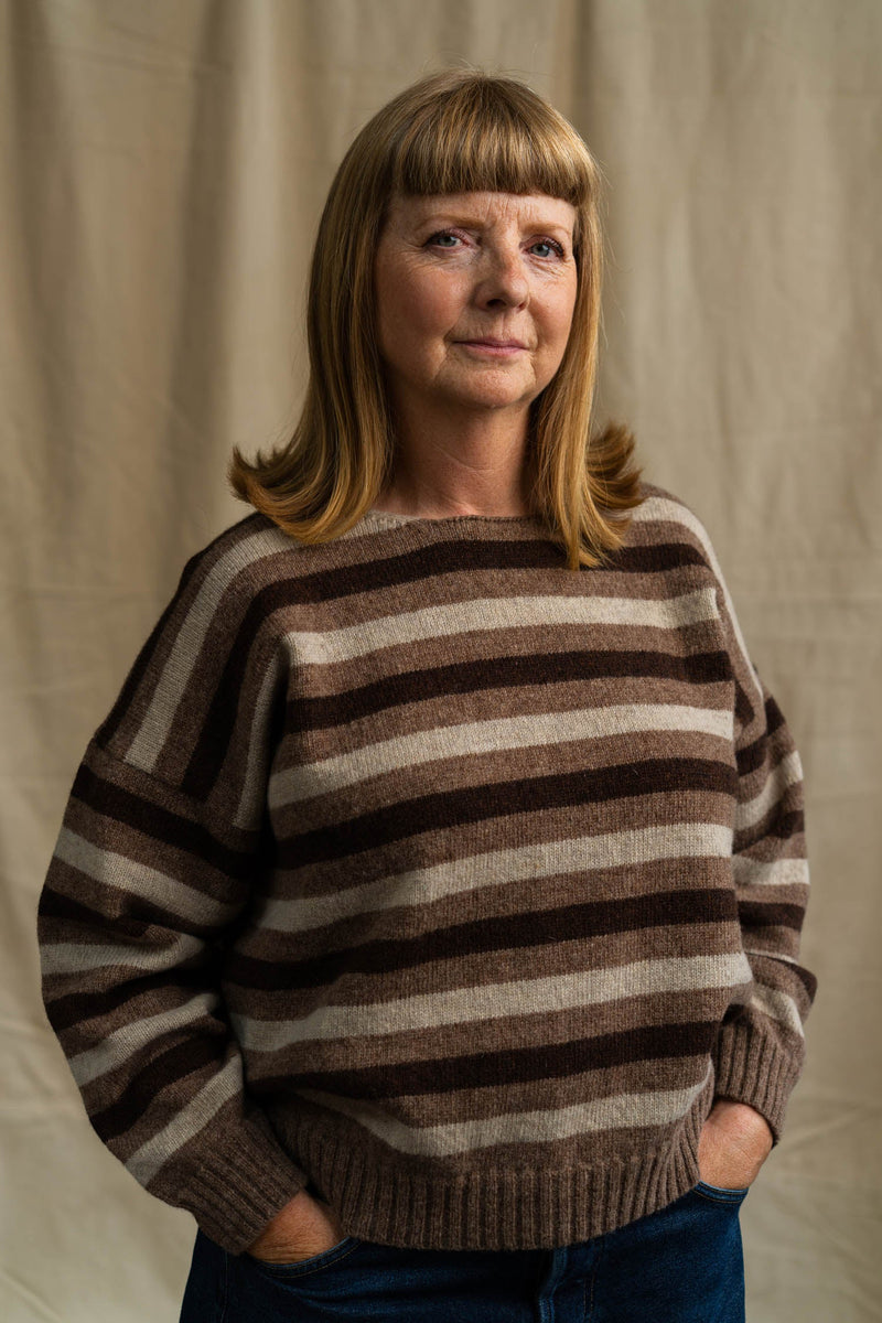 Woman wearing a brown striped sweater against a plain background