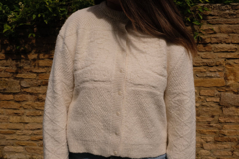 Ivory alpaca cardigan showcasing textured details, a relaxed fit, and sustainable knitwear cardigan design.