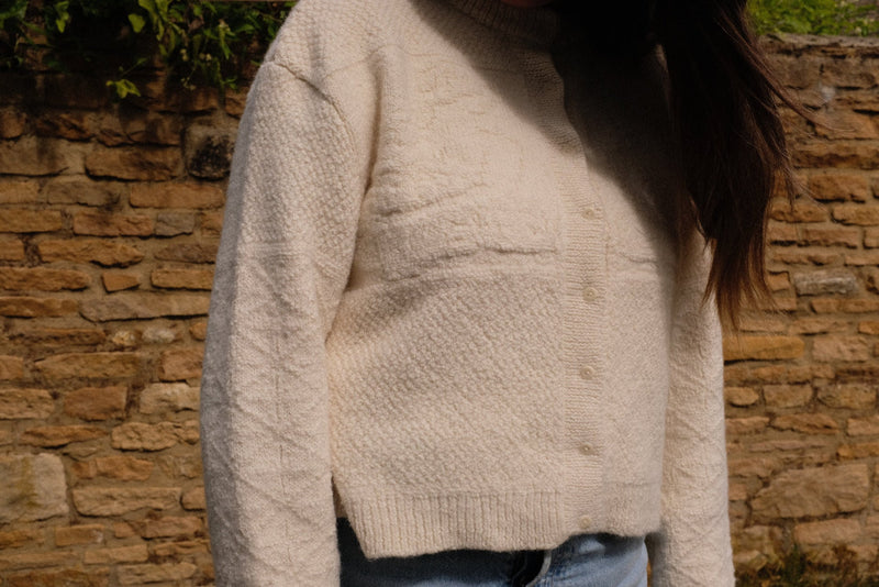 Sustainable knitwear cardigan in ivory alpaca worn casually, highlighting its soft texture and relaxed fit.