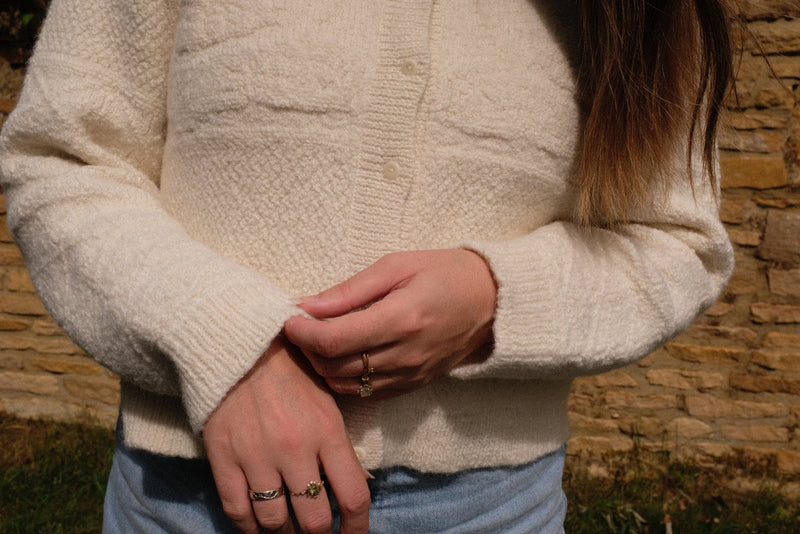 Model wearing an ivory sustainable knitwear cardigan with textured details, perfect for casual outfits.