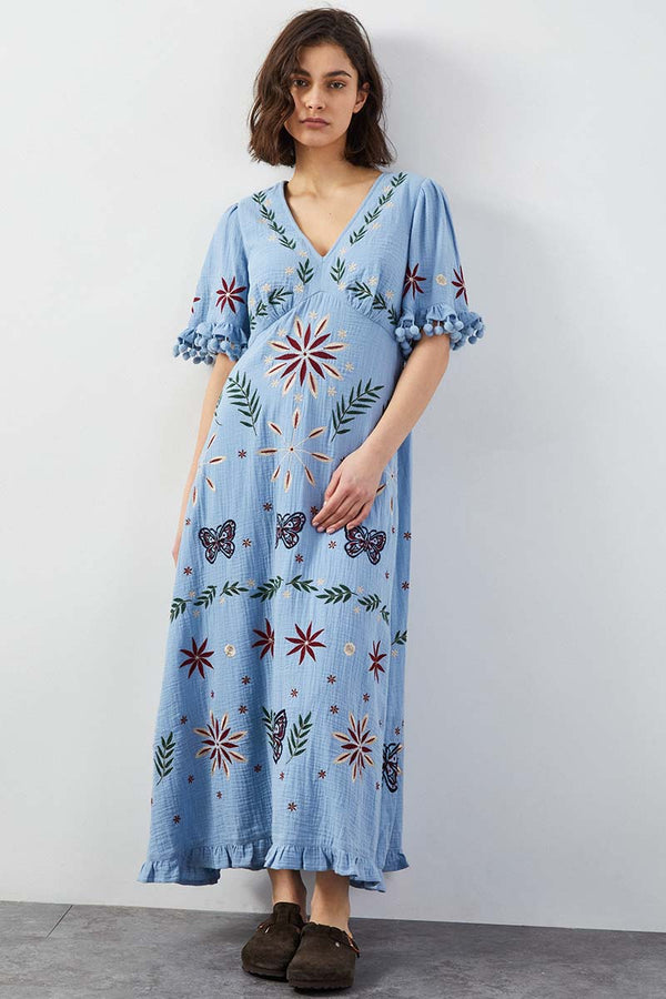 Model wears East Heritage Mererid blue embroidered dress.