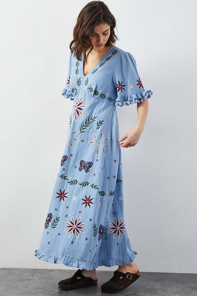 Model wears East Heritage Mererid blue embroidered dress.