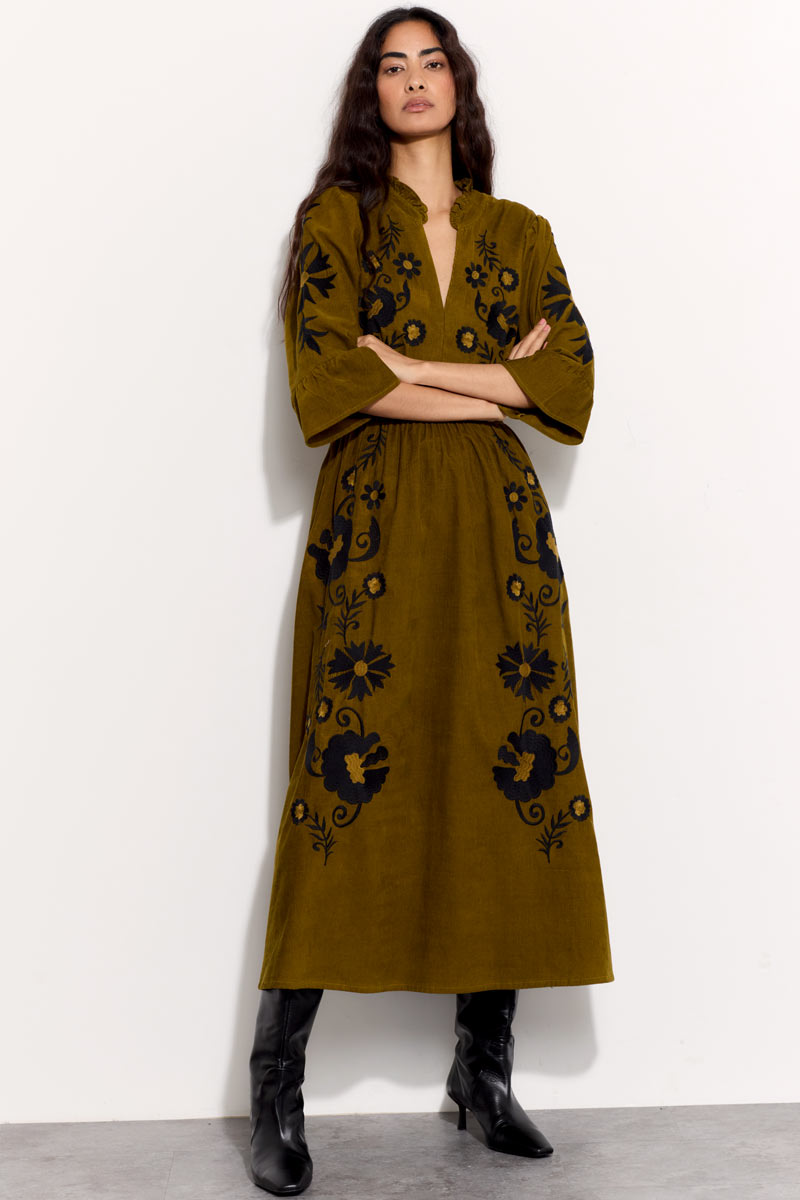 Model wears East Odelia  olive cord embroidered dress with black boots.