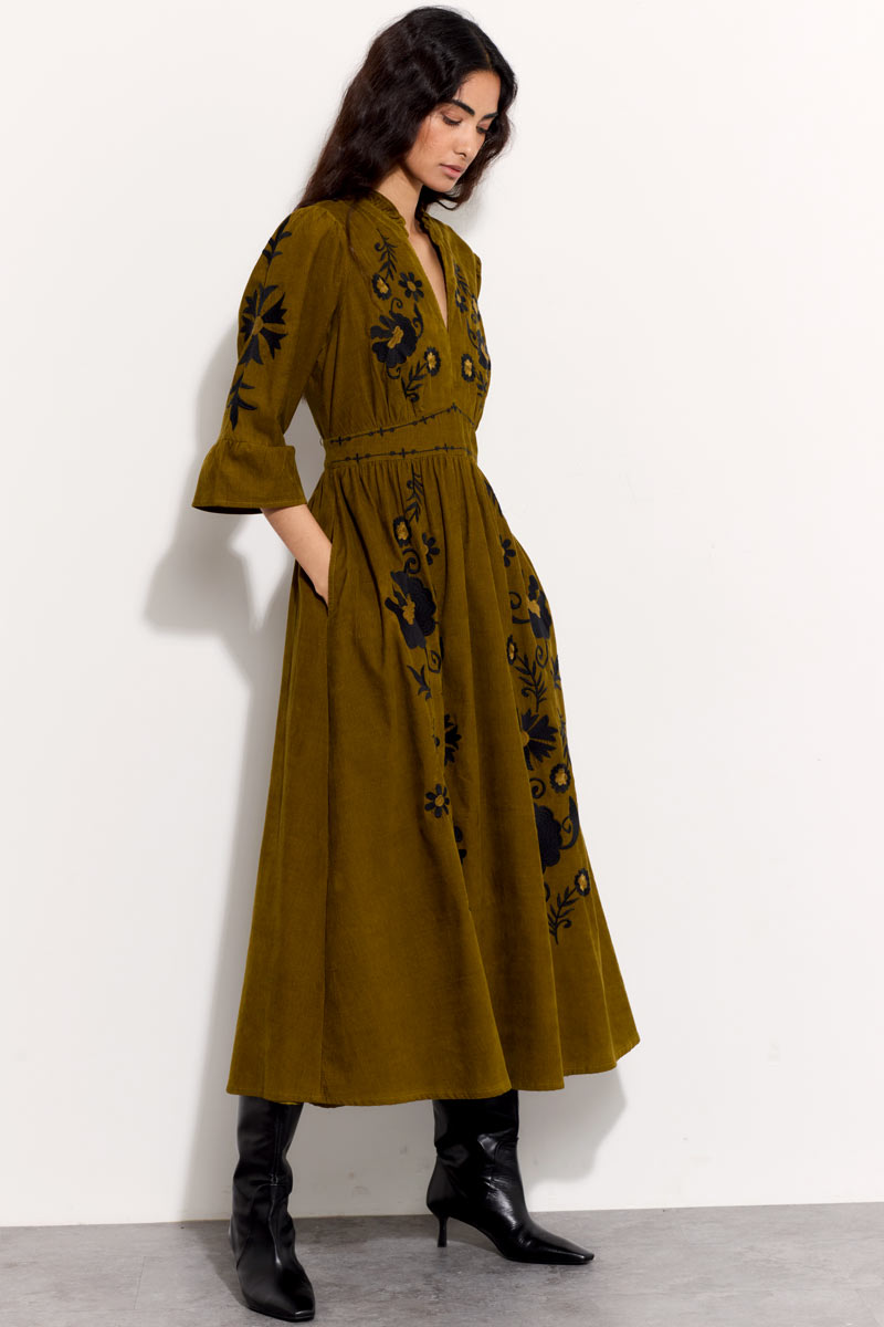 Model wears East Odelia  olive cord embroidered dress with black boots.