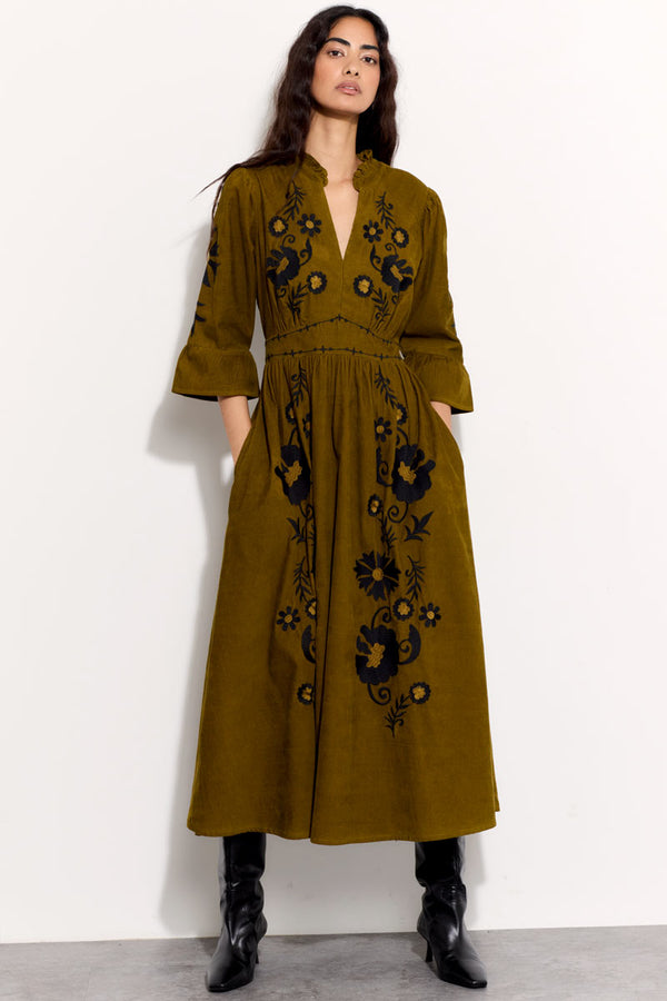 Model wears East Odelia  olive cord embroidered dress with black boots.