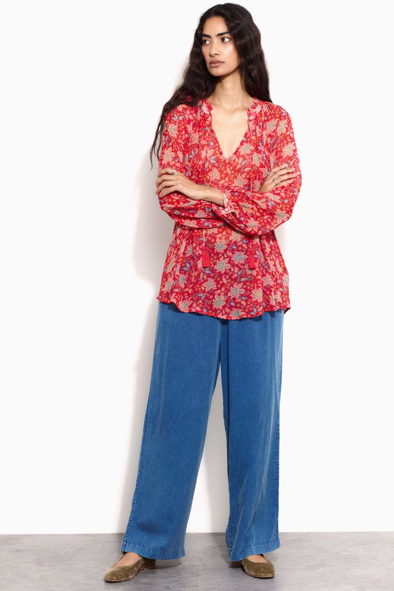 Model wears East Becca Red Top with blue jeans and velvet pumps.