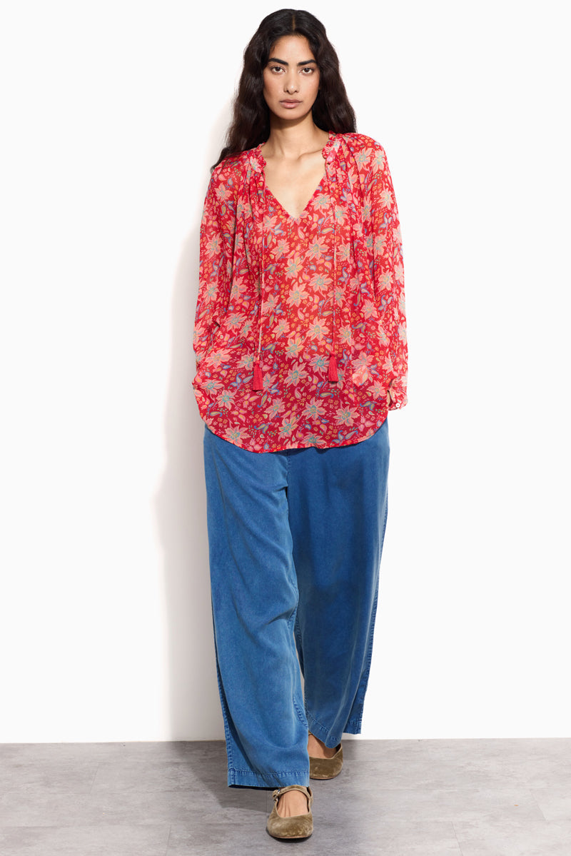 Model wears East Becca Red Top with blue jeans and velvet pumps.