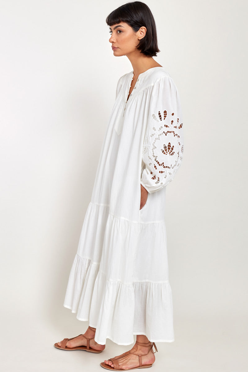 Side view of model wearing Bridget White Organic Cotton Embroidered Dress, hands in pockets