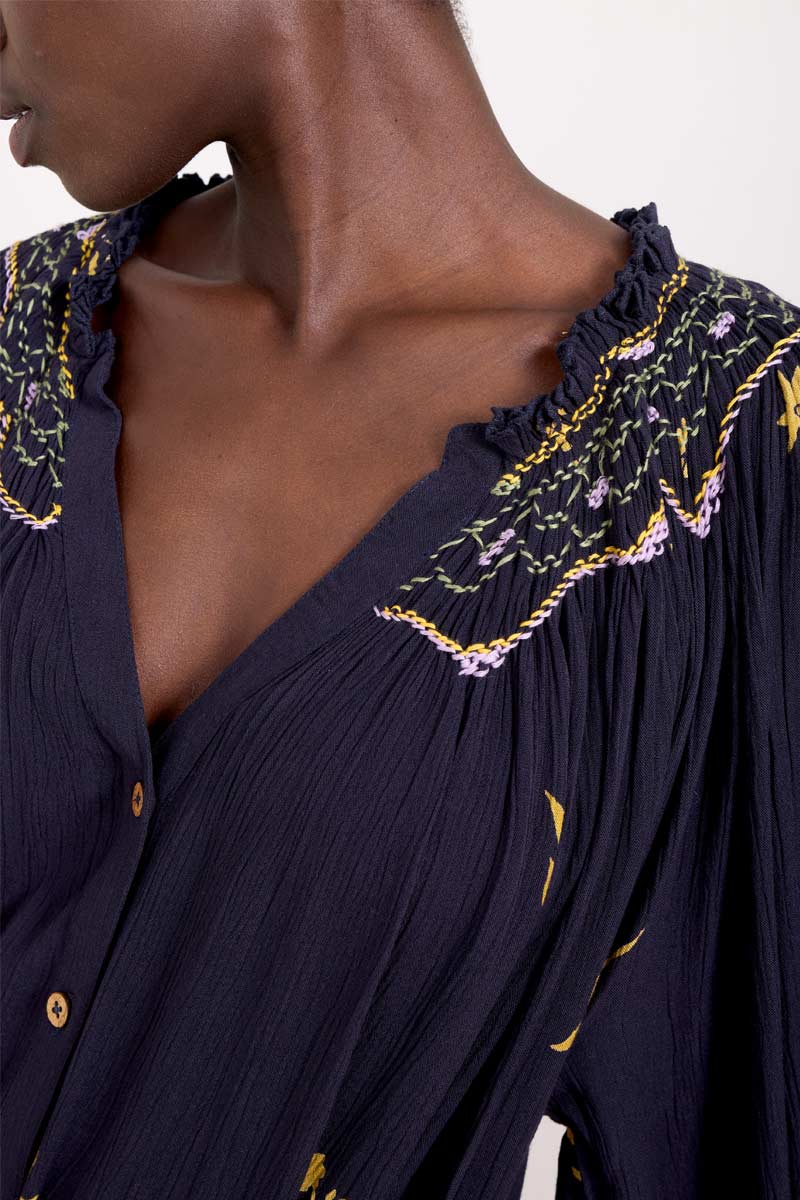 Close up with detail of embroidery of model wearing East Miranda Dress
