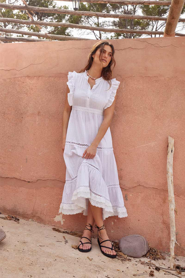 Model leans against a wall wearing East Heritage Peyton White Organic Cotton Dress