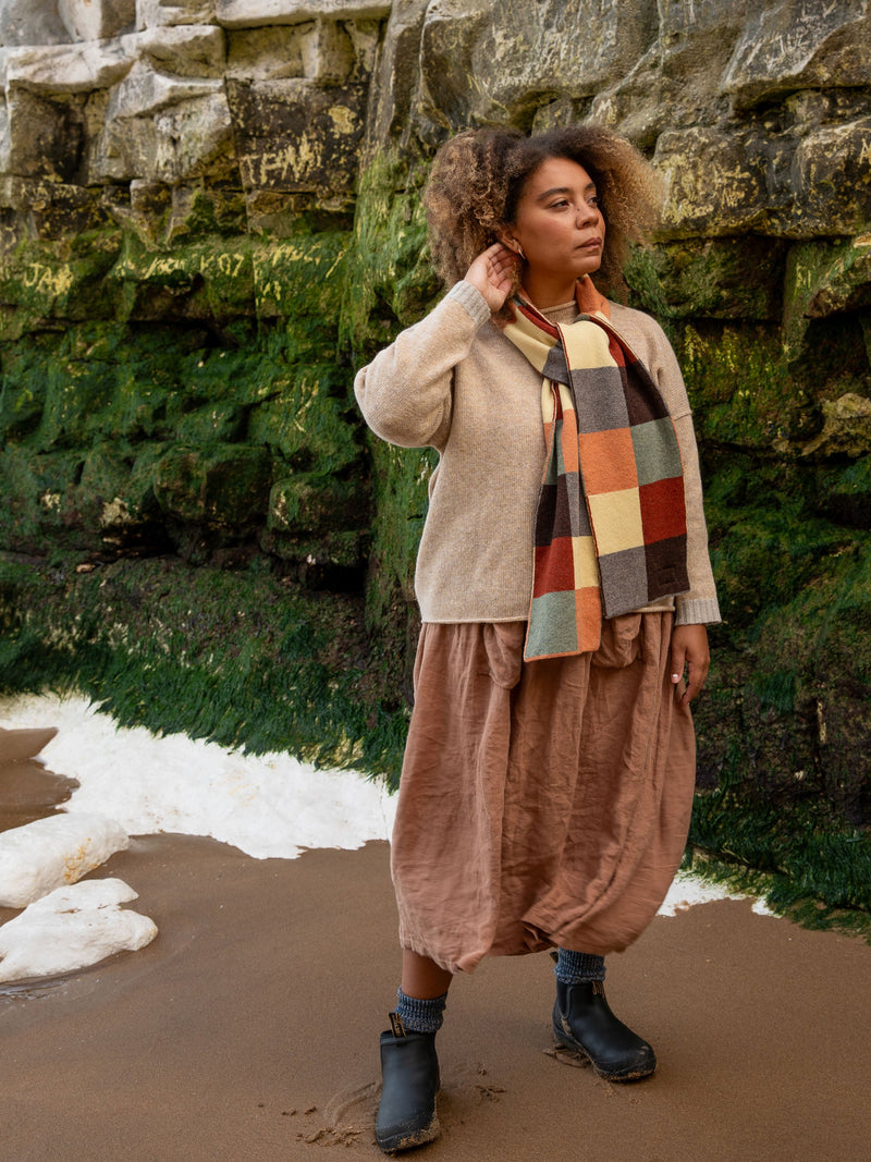 Model wears British Made Merino Chequerboard Pattern Unisex Scarf in Salmon, Light Green, Rust Red, Vole, Light Yellow & Dark Brown