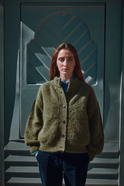 Person wearing a green L'ENVERS cardigan standing 