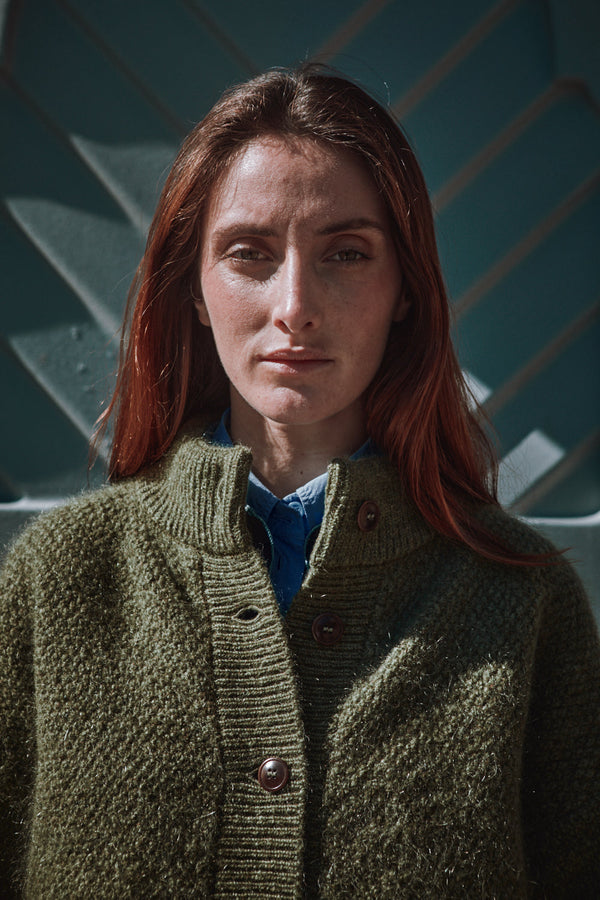 Person wearing a green L'ENVERS cardigan standing 
