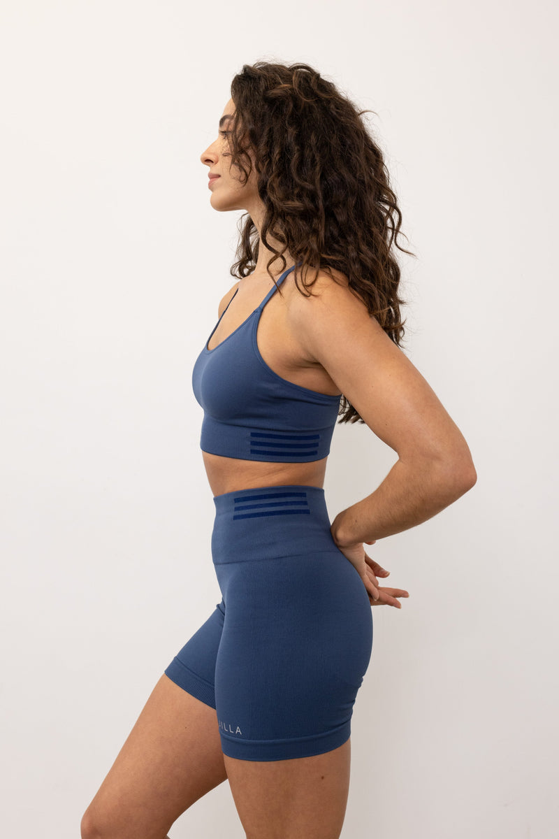 Meet our new denim blue Tone & Lift Recycled Sports Bra! Crafted for comfort and functionality, it's perfect for your active lifestyle. Made with sweat-wicking fabric and adjustable straps, it offers support and adaptability. With stylish details and light to medium support, it's ideal for yoga, pilates, and beyond. Elevate your workout with sustainable style by Jilla Active