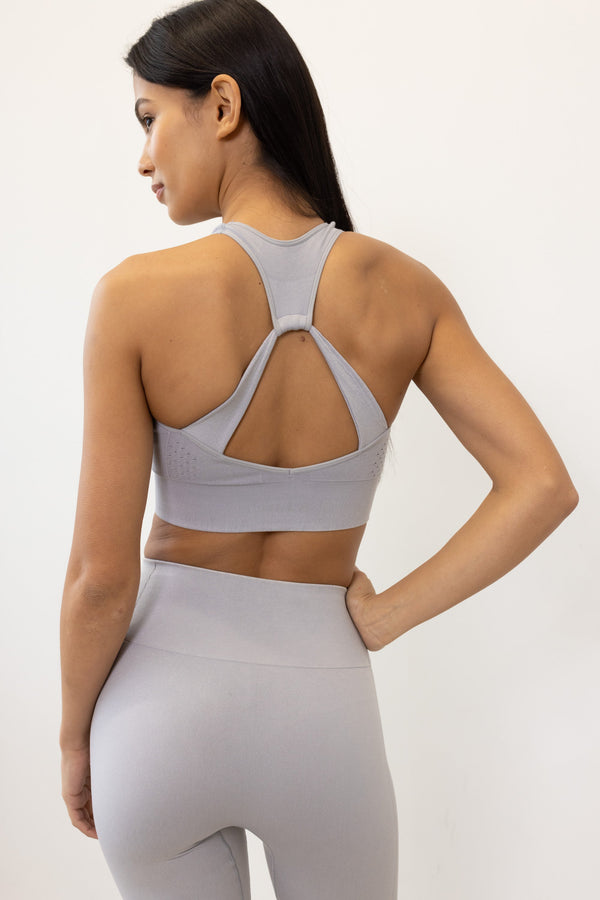 Meet our gery Aquarius Recycled Sports Bra - uniquely textured and stylish, perfect for yoga, barre, and more. Crafted from soft recycled seamless fabric, it offers light to medium support with a high neckline and statement back shape. Pair with our matching leggings for a seamless studio-to-street look. Enjoy versatile support and comfort, customizable with removable pads.