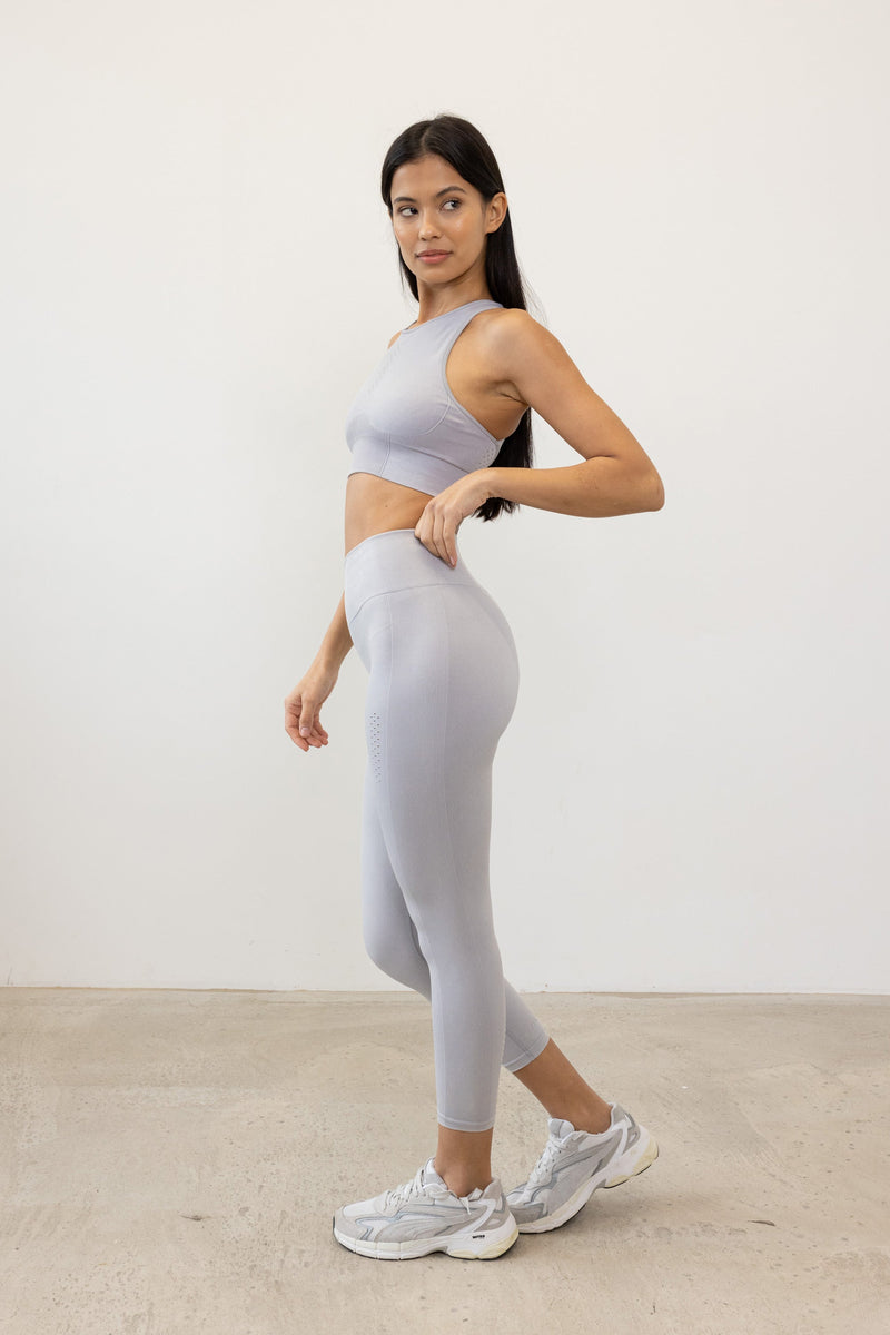 Meet our gery Aquarius Recycled Sports Bra - uniquely textured and stylish, perfect for yoga, barre, and more. Crafted from soft recycled seamless fabric, it offers light to medium support with a high neckline and statement back shape. Pair with our matching leggings for a seamless studio-to-street look. Enjoy versatile support and comfort, customizable with removable pads.