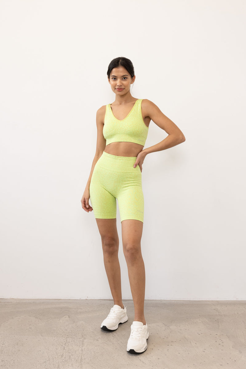 Get summer-ready with our green Sahara Recycled Sports Bra, seamlessly knitted in our new animal jacquard. Designed with a flattering V-neck shape, comfortable straps, and a wide underband, this bra offers light to medium support for low-impact studio exercise, cycling, and gym sessions. The double-layered fabric ensures support and flexibility, while removable pads allow you to customize your fit. Pair it with the matching shorts for a studio-to-street look from sustainable activewear brand Jilla Active