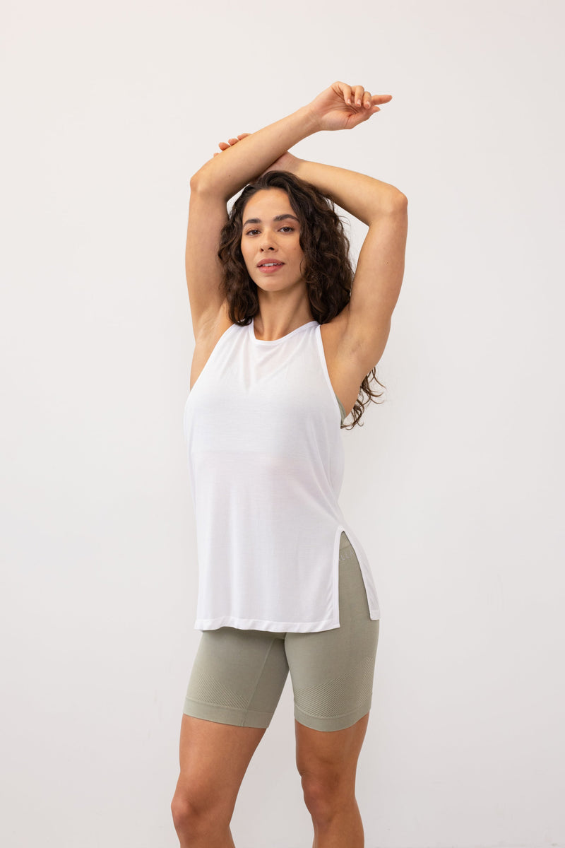 Stay cool and comfortable in the white Revolve Bamboo Tank Top from Jilla Active. Crafted from a bamboo blend, it's perfect for warm days and workouts. With a seamless knit for a smooth fit, side split for versatile styling, and twisted racerback for maximum movement, it's ideal for studio classes, runs, or gym sessions.
