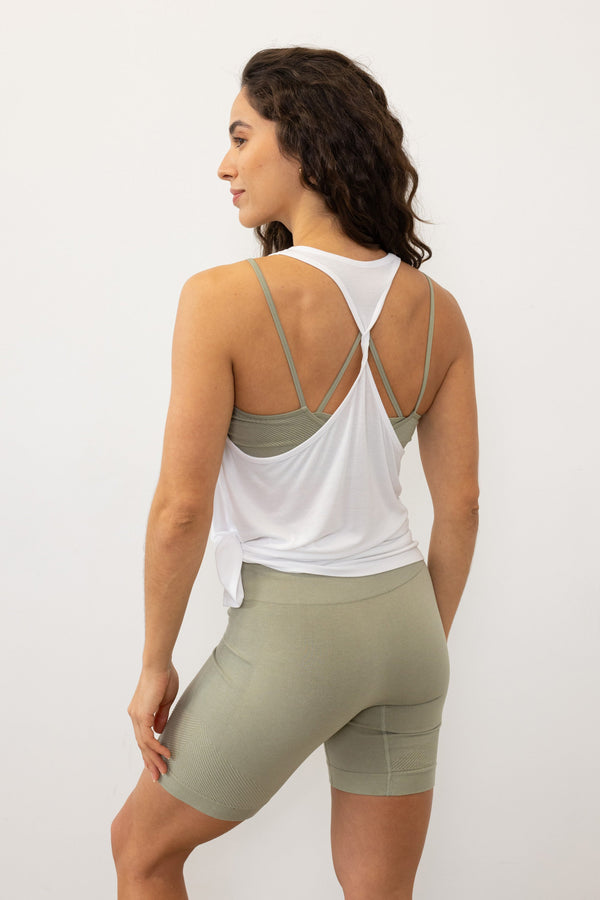 Stay cool and comfortable in the white Revolve Bamboo Tank Top from Jilla Active. Crafted from a bamboo blend, it's perfect for warm days and workouts. With a seamless knit for a smooth fit, side split for versatile styling, and twisted racerback for maximum movement, it's ideal for studio classes, runs, or gym sessions.