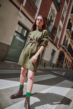 Woman in a green dress standing on a city street.