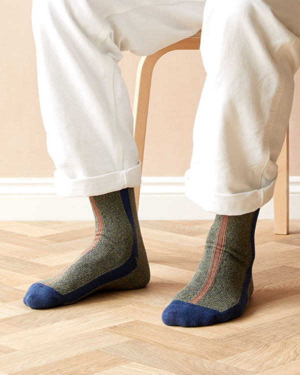 Person wearing patterned socks with blue toes and heels on a wooden floor.