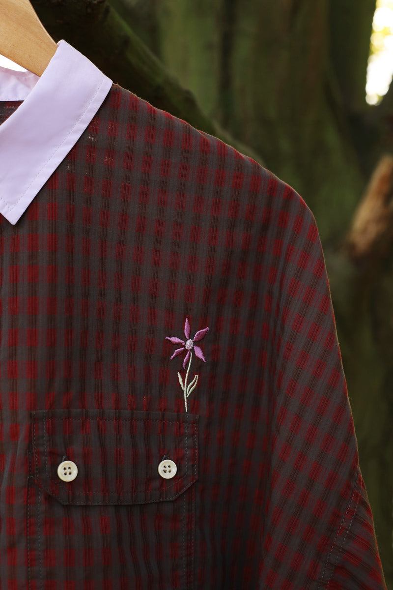 Close up of Saywood' red check Jules Utility Shirt with lilac collar and utility pockets. The flower embroidery is seen just above the pocket. A tree is in the background. Made in Britain.