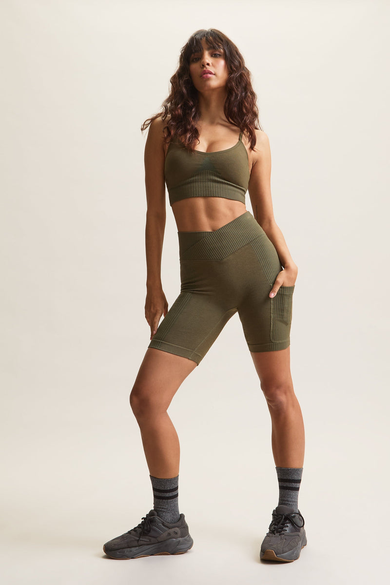 Women's HRMN8 green Venus Block Shorts in a seamless, chunky rib design, featuring a high-waisted crossover waistband for a flattering, sculpted fit. Designed for comfort and style with a supportive, second-skin feel. Includes a side pocket for added convenience. Perfect for athleisure, casual wear, and everyday movement. Pairs with the Venus Rib Bra for a coordinated set.