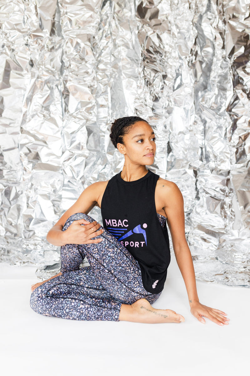 side view of woman wearing black terrazzo print leggings in a yoga pose showing the stretch of the recycled fabric 