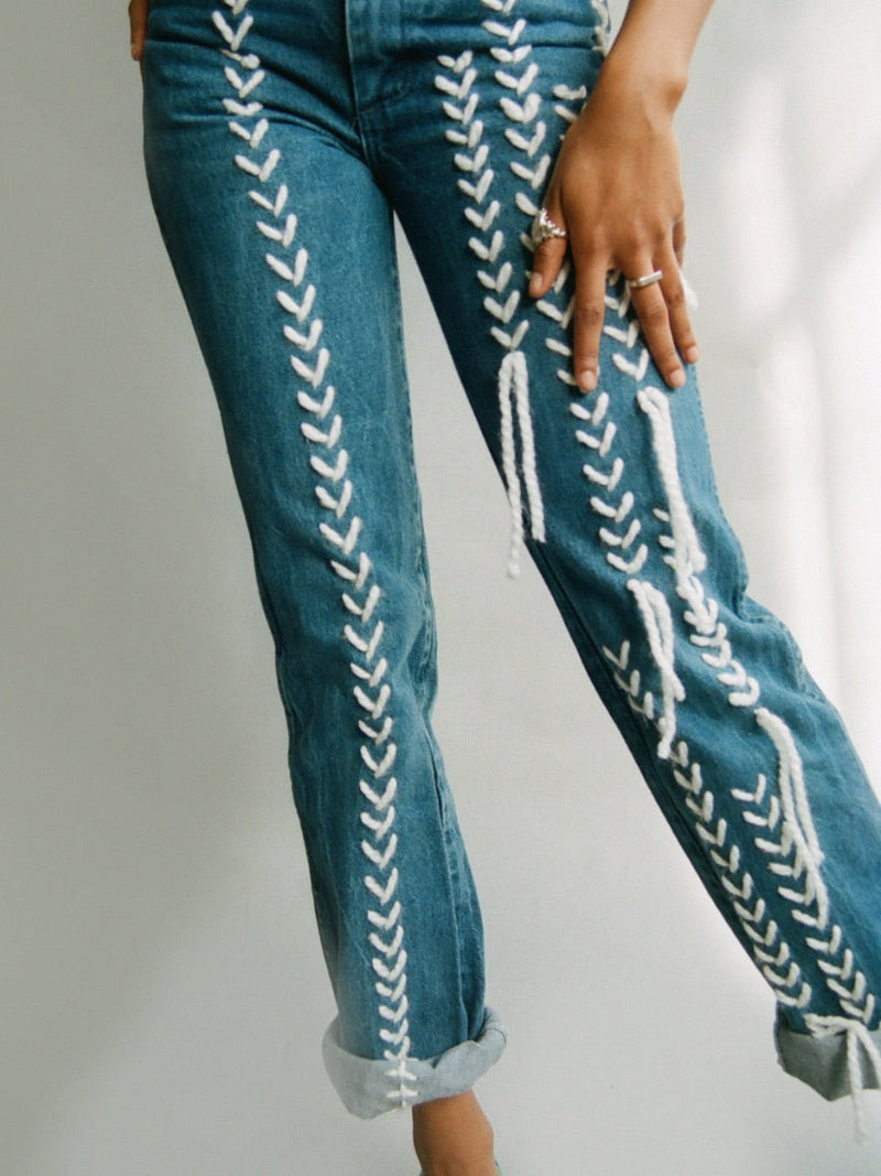 Fanfare Label sustainable women’s clothing brand UK. Our upcycled jeans are high-waisted, blue denim and made from recycled denim. We decorate every jean with white embroidery thread.