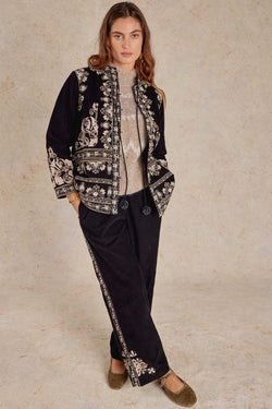 Front view of model wearing Eveline Trousers, legs crossed over one another