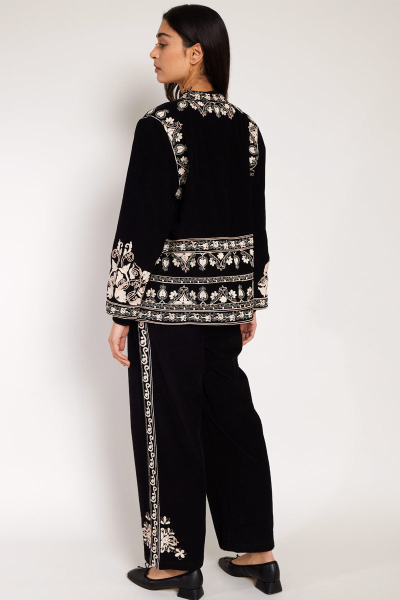Back view of Model wearing East Eveline embroidered trousers, with East eveline embroidered jacket