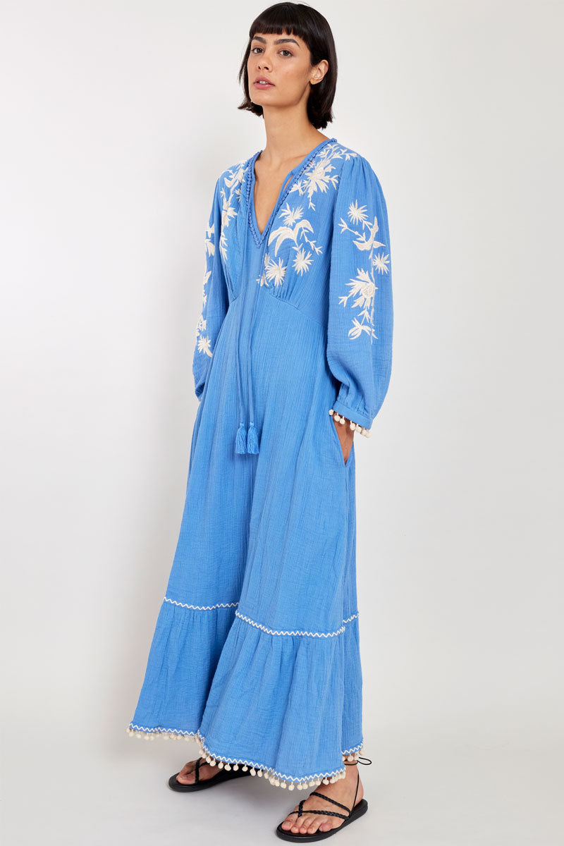 Model wears East Fern Embroidered Blue Cotton Gauze Dress hands in pockets